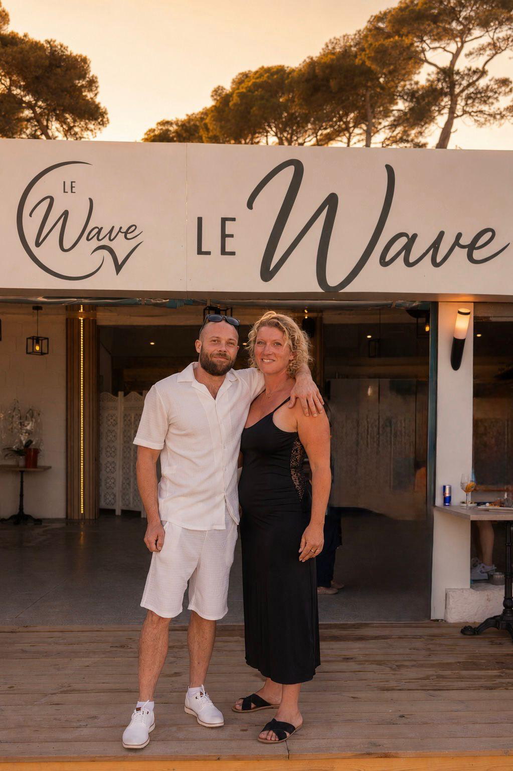 Couple devant l'enseigne du restaurant Le Wave à Saint-Aygulf au coucher de soleil